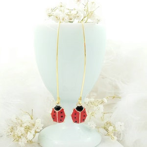 May include: A pair of gold dangle earrings with red and black ladybug charms.