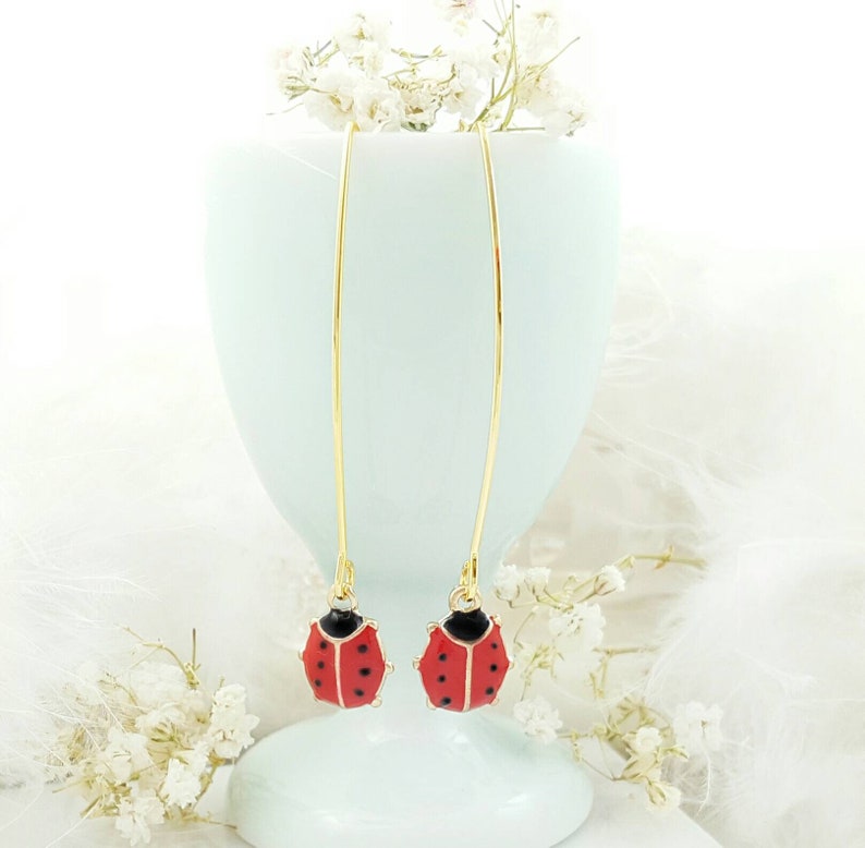 May include: A pair of gold dangle earrings with red and black ladybug charms.