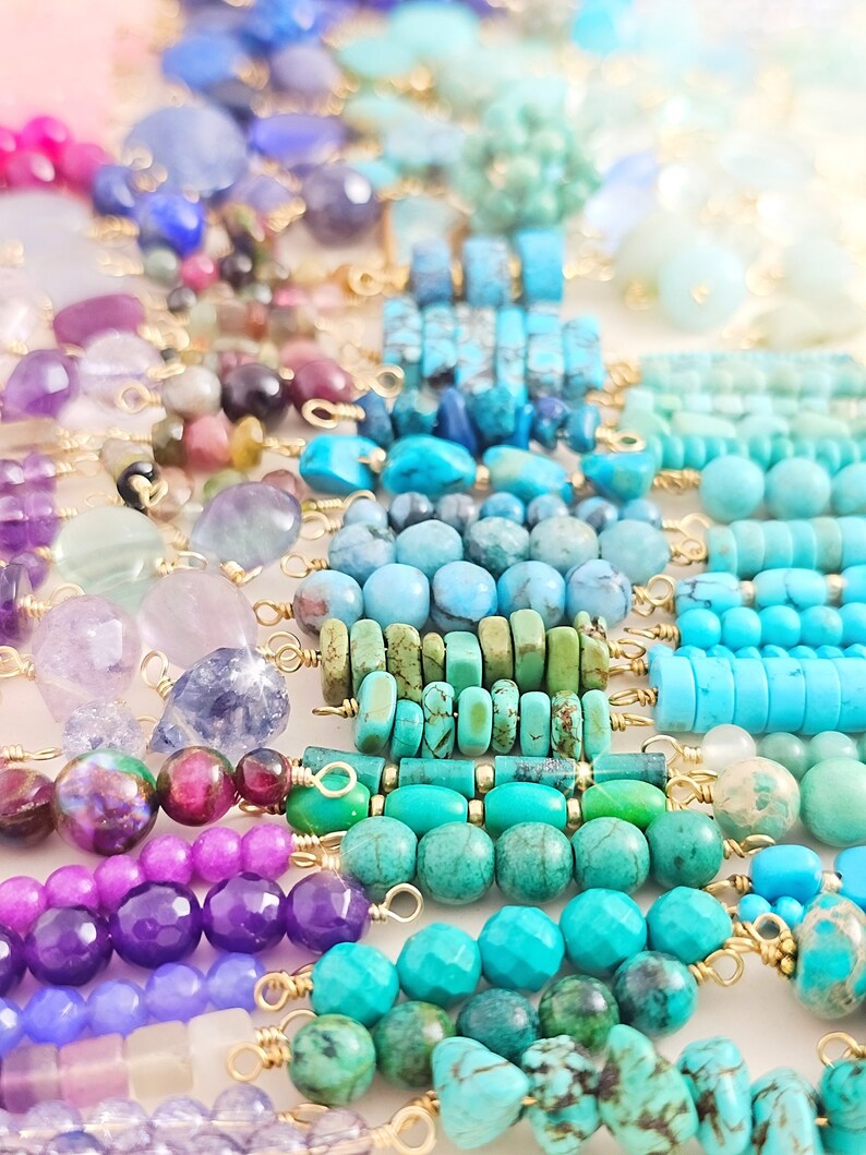 Puede incluir: Surtido de cuentas de piedras preciosas de colores enhebradas en alambre dorado. Las cuentas son de varias formas y tama&ntilde;os, incluyendo redondas, ovaladas y rectangulares. Los colores incluyen morado, azul, verde y turquesa.