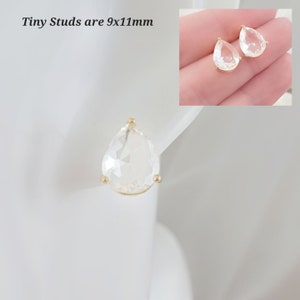 Puede incluir: Un par de pendientes de cristal transparente en forma de l&aacute;grima con engastes dorados. Los pendientes miden 9x11mm. Tiny Studs are 9x11mm.