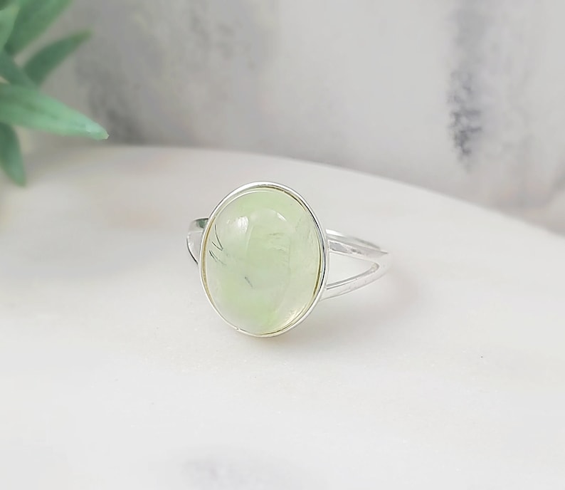 This silver prehnite ring is made with a 12x15mm oval, pale green, genuine prehnite gemstone cabochon which we set in a 925 Sterling silver ring bezel. This US size 5.75 or 8.25 green ring makes a great August birthstone jewelry gift for her.