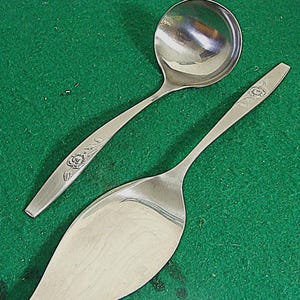 May include: Two silver serving utensils with floral designs. A silver ladle and a silver cake server.
