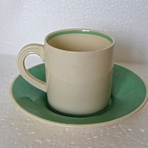 May include: A white ceramic coffee cup with a green rim and a matching green saucer.