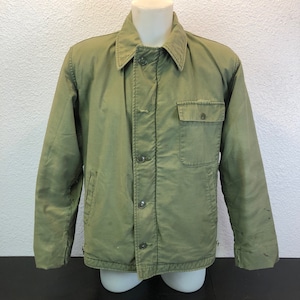 May include: A green utility jacket with a button-up front and a single chest pocket.