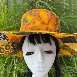 Janis: Sombrero para el sol reversible de ala ancha y flexible estilo hippie, sombrero de copa -2hatsin1; tela de corteza/parches artificiales con diseño floral retro llamativo - amarillo, naranja y marrón - talla pequeña