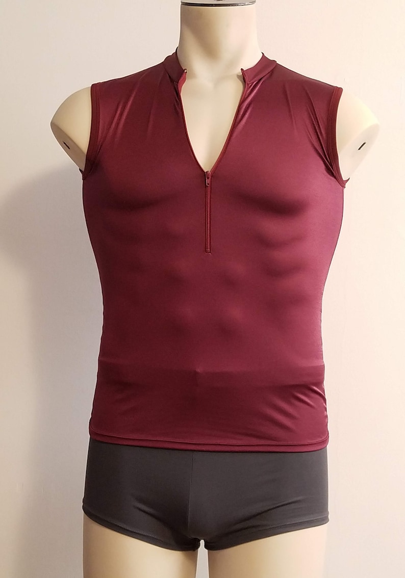 May include: A sleeveless burgundy shirt with a zipper up the front. The shirt is made of a shiny, smooth fabric.