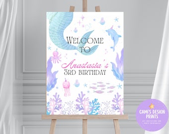 May include: A welcome sign for a 3rd birthday party featuring a mermaid tail, a dolphin, and other sea creatures. The sign reads "Welcome to Anastasia's 3rd Birthday".