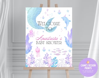 May include: A welcome sign for a baby shower with a mermaid tail, a dolphin, and a jellyfish. The sign says "Welcome to Anastasia's Baby Shower".