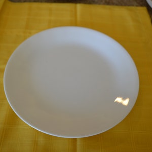 Könnte beinhalten: Ein weißer Keramik-Dinnerteller auf einer gelben karierten Tischdecke.