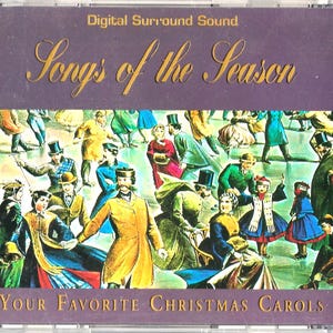 Pode incluir: Uma caixa de CD com o título "Songs of the Season" em letras douradas sobre uma ilustração colorida de pessoas patinando no gelo. O texto "Your Favorite Christmas Carols" está na parte inferior. A caixa está em um estojo de plástico transparente.