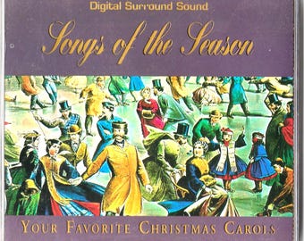 Könnte beinhalten: Eine CD-Hülle mit dem Titel "Songs of the Season" in goldener Schrift über einer farbenfrohen Illustration von Menschen, die Schlittschuh laufen. Der Text "Your Favorite Christmas Carols" steht unten. Die Hülle befindet sich in einer transparenten Kunststoffhülle.