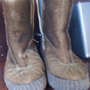 Puede incluir: Un par de botas de piel marrón con una cremallera en el lateral. Las botas tienen una suela gruesa y texturizada.