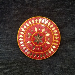 May include: A round, pink and gold decorative object with a star design in the center. The object is made of glass and has a mirrored finish.