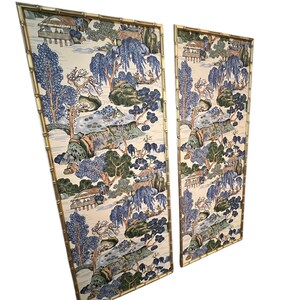 May include: Two decorative wall panels with a bamboo-style gold frame. The panels feature a scenic landscape design with blue, green, and beige tones. The artwork depicts trees, buildings, and water features, creating a serene aesthetic.