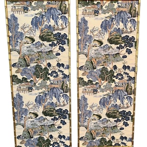 May include: Two decorative wall panels with a bamboo-style gold frame. The panels feature a cream-colored background with a blue and green Asian-inspired landscape design. The artwork depicts trees, buildings, and figures.