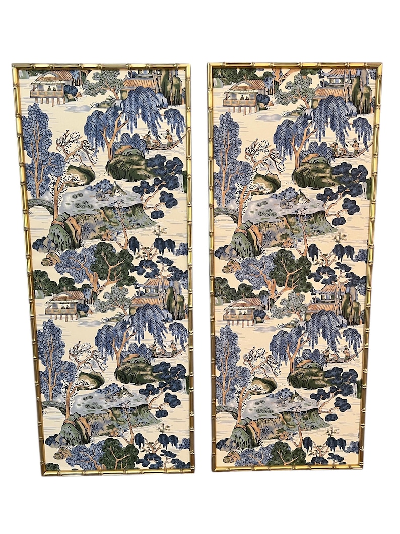May include: Two decorative wall panels with a bamboo-style gold frame. The panels feature a cream-colored background with a blue and green Asian-inspired landscape design. The artwork depicts trees, buildings, and figures.