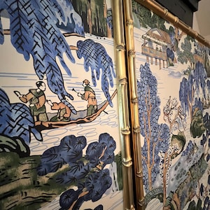 May include: A decorative panel featuring a scenic landscape with figures in a boat, trees, and a small building. The artwork is predominantly blue, green, and beige, framed by a gold bamboo-style border.