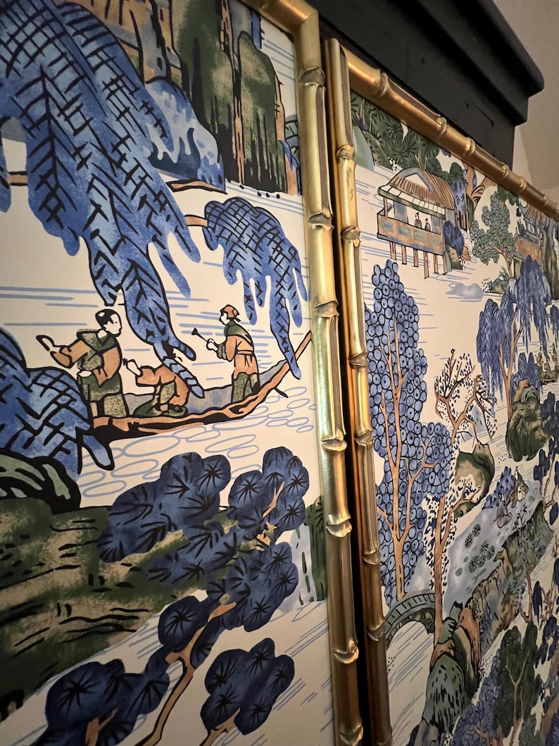 May include: A decorative panel featuring a scenic landscape with figures in a boat, trees, and a small building. The artwork is predominantly blue, green, and beige, framed by a gold bamboo-style border.