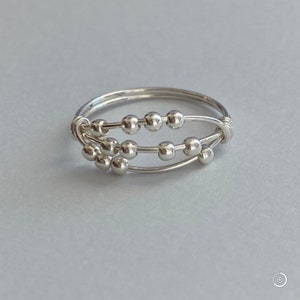 May include: A silver ring with three bands of wire, each with a row of small silver beads.
