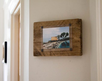 May include: A rustic wooden picture frame with a clear acrylic insert, displaying a photograph of a building with a pool in the background.