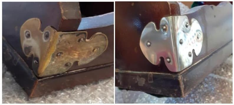 Op de afbeelding: Close-up van twee houten hoeken met decoratieve metalen accenten. De ene hoek heeft een messing accent, terwijl de andere een zilveren accent heeft. Beide accenten zijn in de vorm van een gestileerd blad.