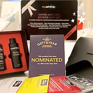 May include: A black gift box set for cleaning and polishing silver and gems. The box contains three bottles of silver cleaning solution, a polishing cloth, and a cleaning cloth. The box is labeled "Nushine Silver and Gem Reviver Gift Set".