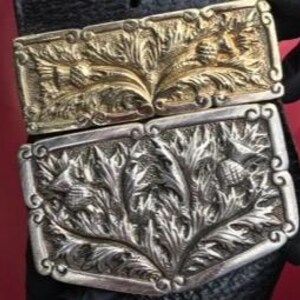 Op de afbeelding: Twee riemgespen met een distelmotief. De bovenste gesp is goud en de onderste gesp is zilver.