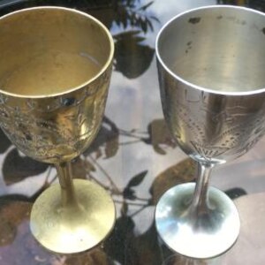 Op de afbeelding: Twee sierlijke zilveren kelken met gegraveerde ontwerpen. De ene kelk is goud en de andere is zilver.