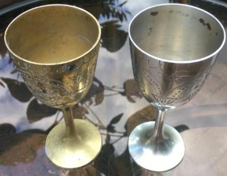 Op de afbeelding: Twee sierlijke zilveren kelken met gegraveerde ontwerpen. De ene kelk is goud en de andere is zilver.