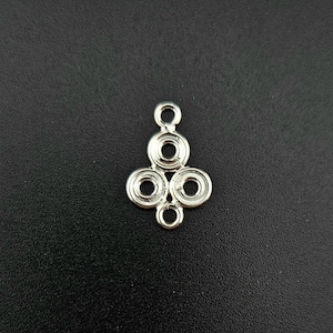 May include: Silver pendant with a circular design. The pendant has four circles, with the top circle being the largest and the bottom three circles being smaller. The pendant has a loop at the top for attaching to a chain.