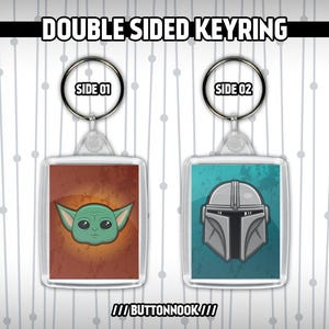 May include: Double-sided keyring with two designs. One side shows a green alien character on a brown background, labelled "SIDE 01." The other side features a silver helmet on a teal background, labelled "SIDE 02." The text "DOUBLE SIDED KEYRING" is at the top.