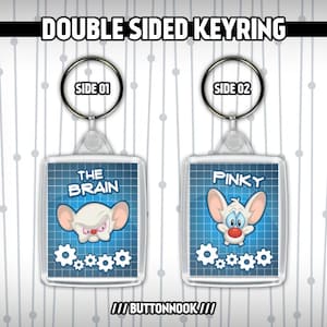 Può includere: Portachiavi a doppia faccia con personaggi dei cartoni animati della serie animata Pinky e il Cervello. Un lato mostra Pinky con il testo "Pinky" e l'altro lato mostra il Cervello con il testo "The Brain".