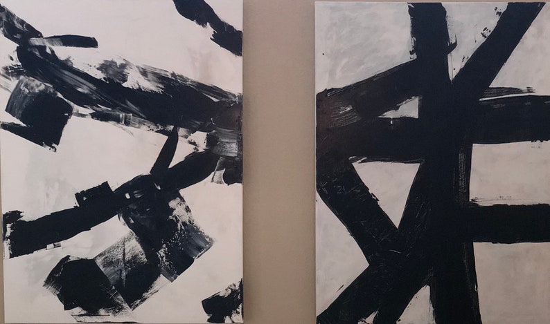 May include: Two abstract paintings with black brushstrokes on a white background. The paintings are side-by-side and are both rectangular in shape.