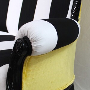 May include: A black and white striped loveseat with a yellow velvet seat and black carved wooden legs.