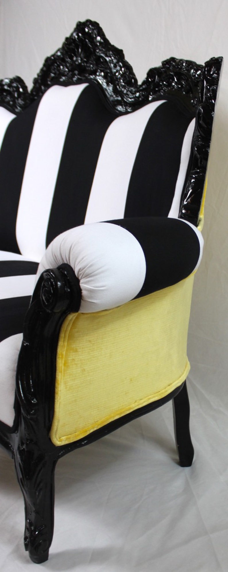 May include: A black and white striped loveseat with a yellow velvet seat and black carved wooden legs.