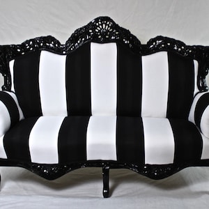 May include: A black and white striped sofa with a black, ornate, carved wooden frame. The sofa has a curved back and arms.