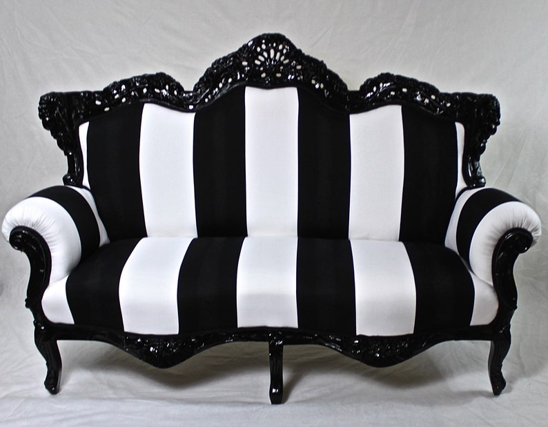 May include: A black and white striped sofa with a black, ornate, carved wooden frame. The sofa has a curved back and arms.