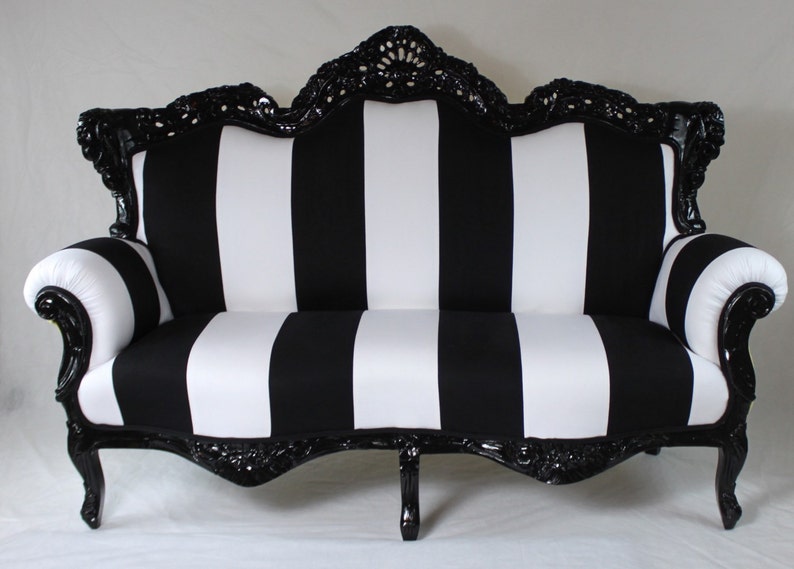 May include: A black and white striped sofa with a black, ornate wooden frame. The sofa has a curved back and arms.