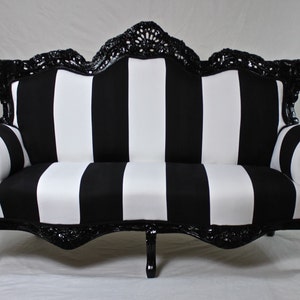 May include: A black and white striped sofa with a black, ornate, carved wooden frame. The sofa has a classic, elegant design.