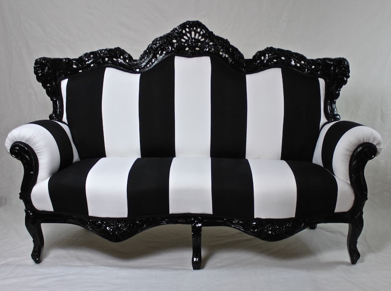 May include: A black and white striped sofa with a black, ornate, carved wooden frame. The sofa has a classic, elegant design.