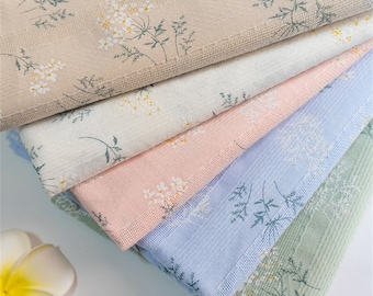 Op de afbeelding: Vijf stukken stof met een bloemenpatroon. De stof is in de kleuren beige, wit, roze, lichtblauw en groen.