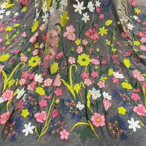 May include: A sheer fabric with embroidered floral designs in shades of pink, yellow, green, and blue. The flowers are various sizes and shapes, creating a delicate and intricate pattern.