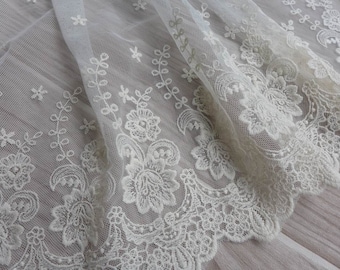 May include: White lace fabric with a delicate floral pattern. The lace has a scalloped edge and is made of a soft, sheer material.