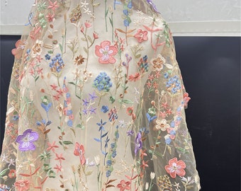 May include: Beige sheer fabric with embroidered floral pattern in shades of pink, blue, green, and purple.