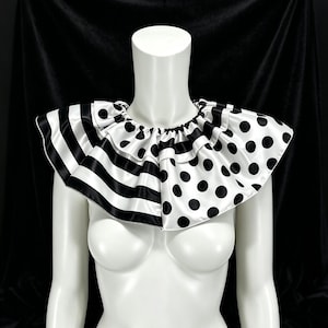 May include: A ruffled neck collar featuring a split design with black and white horizontal stripes on one side and black polka dots on a white background on the other. The accessory is gathered at the neckline with a visible elasticised seam.