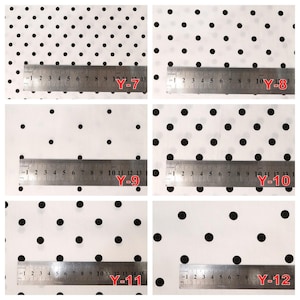 May include: A collection of six white fabric swatches featuring black polka dot patterns of varying sizes, each labeled with a red code from Y-7 to Y-12 and displayed with a metal ruler showing measurements in centimeters for scale.