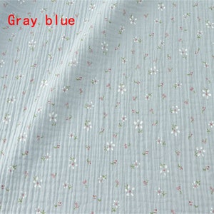 May include: A light blue fabric with a small white floral pattern. The fabric has a slightly textured surface.