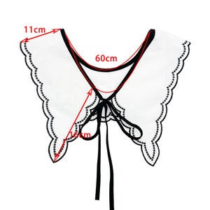 May include: White faux collar with black trim and a scalloped edge. The collar has a black ribbon tie and measures 11 inches wide and 16 inches long.