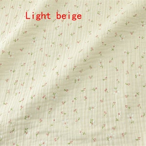 May include: Light beige fabric with a small white floral pattern.