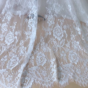 May include: White lace fabric with a floral pattern. The lace has a scalloped edge.